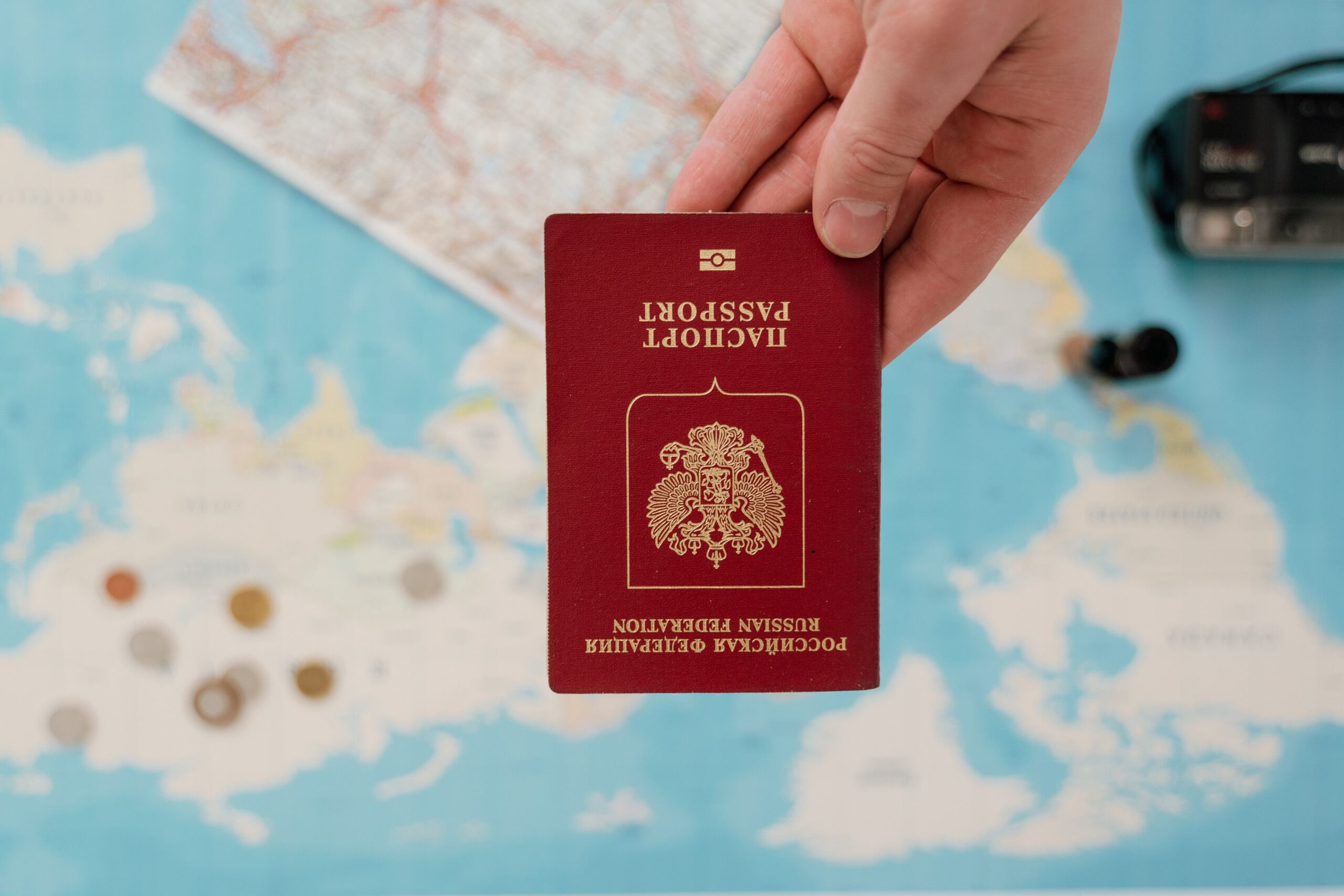 Dłoń trzymająca czerwony paszport na tle rozłożonej mapy